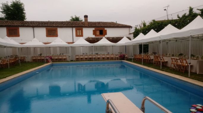 Piscina rodeada de sombrillas y sillas, en un espacio al aire libre.